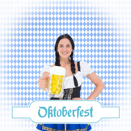 Pretty oktoberfest girl holding beer tankard against blue patternの写真素材