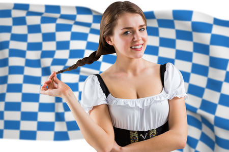 Pretty oktoberfest girl smiling at camera against blue and white flagの写真素材