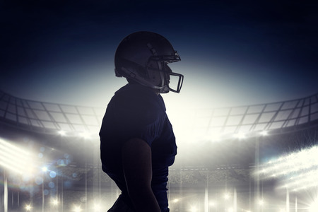 Side view of silhouette American football player standing against rugby stadiumの写真素材