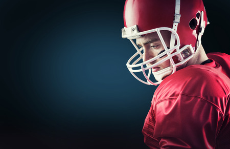 Concentrated american football player against blue background with vignetteの写真素材