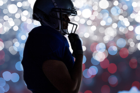 Side view of silhouette American football player wearing helmet against glowing backgroundの写真素材