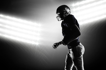 Silhouette American football player walking against spotlightの写真素材