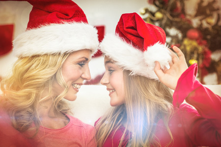 Festive mother and daughter smiling at each other at home in the living roomの写真素材