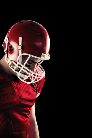 Amercian football player having his helmet on her head  against blackの写真素材