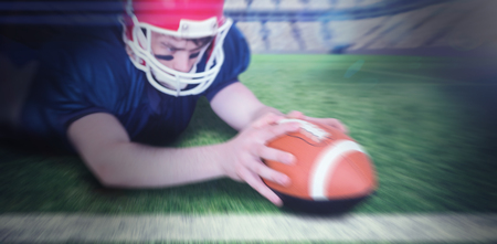 American football player scoring a touchdown against rugby pitch
