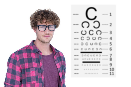 Handsome man wearing geek glasses over white background against eye testの写真素材