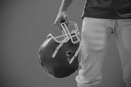 An american football player taking his helmet on hand  against red backgroundの写真素材