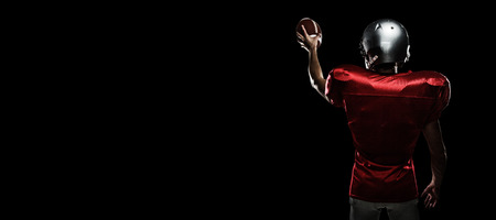 Rear view of sportsman in red jersey holding ball against blackの写真素材