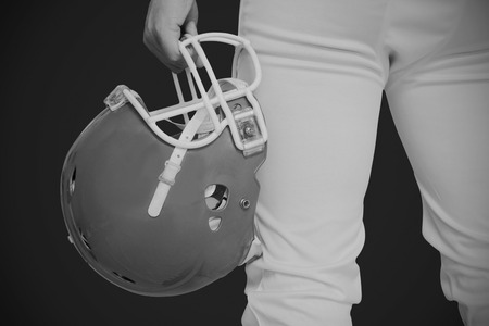 American football player holding a helmet against blackの写真素材