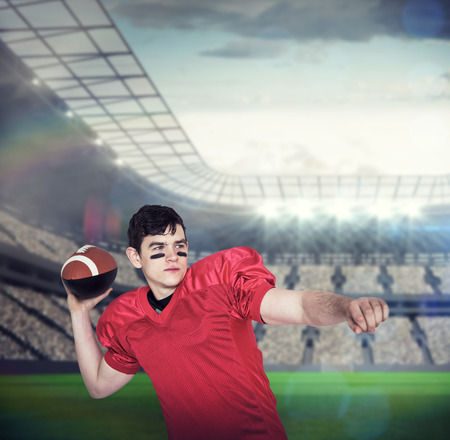 American football player throwing a ball against large football stadium with lightsの写真素材