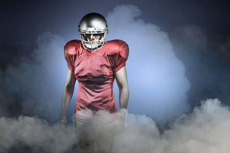 Confident American football player against cloudy skyの写真素材