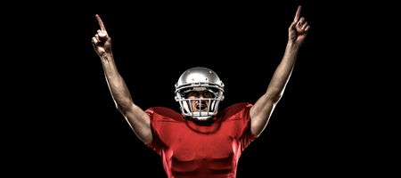 American football player with arms raised standing against black