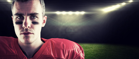 Portrait of a serious american football player looking at camera against rugby stadiumの写真素材