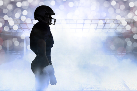 Side view of silhouette American football player standing against glowing backgroundの写真素材