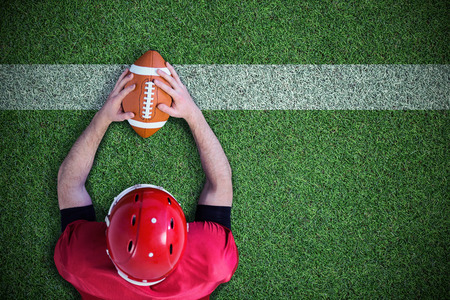 American football player reaching football against pitch with lineの写真素材