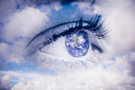 Close up of female blue eye against blue sky with white cloudsの写真素材