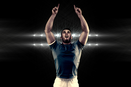 Rugby player cheering and pointing against spotlightsの写真素材