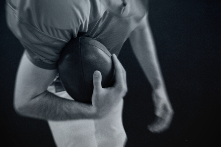 American football player taking a ball on her hand  against blackの写真素材