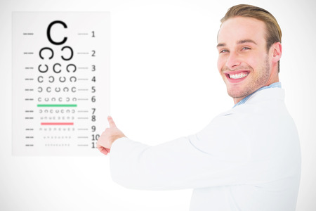Smiling optician pointing eye test against eye testの写真素材