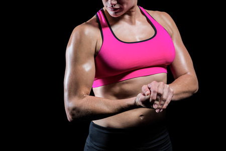 Muscular woman flexing her arm on black backgroundの写真素材