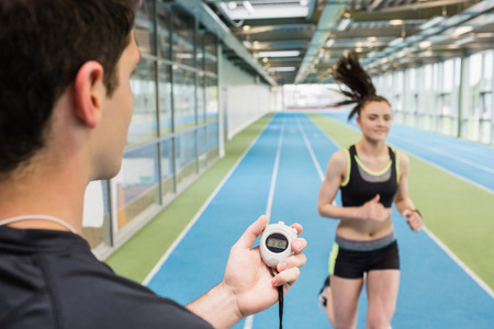 Trainer timing woman on the track at the gym