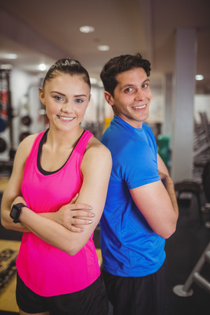 Fit couple smiling at camera at the gymの写真素材
