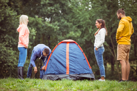 Happy friends setting up their tent in the countrysideの写真素材