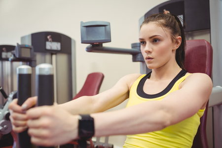 Fit woman using weights machine at the gym