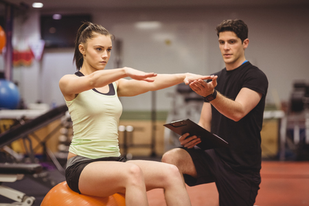 Fit woman working out with trainer at the gymの写真素材