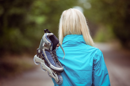 Happy blonde holding inline skates in the countrysideの写真素材