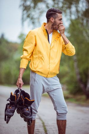 Handsome man holding inline skates in the countrysideの写真素材