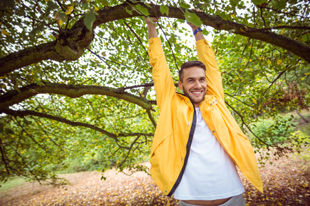 Handsome man hanging from tree in the countrysideの写真素材