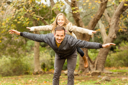 Father and his daughter imitatimg plane on an autumns day