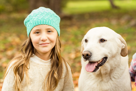 Smiling young girl with her dog on an autumns day