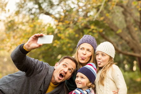 Smiling young family taking selfies on an autumns day