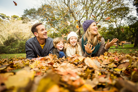 Smiling young family throwing leaves around on an autumns dayの写真素材
