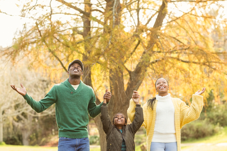 Portrait of a young family with arms raised on an autumns day