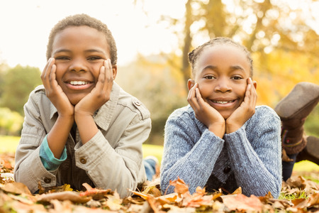 Portrait of young children lying in leaves on an autumns dayの写真素材