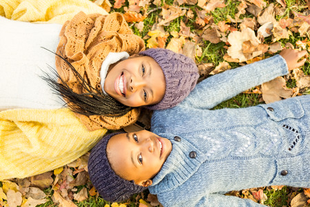 Young mother with her daughter lying in leaves on an autumns dayの写真素材