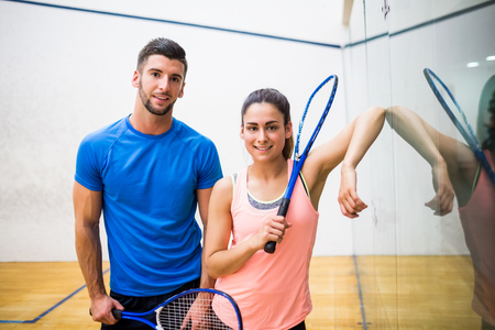 Happy couple about to play squash in the squash court