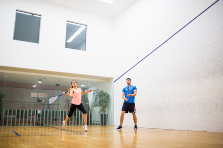 Couple playing a game of squash in the squash courtの写真素材