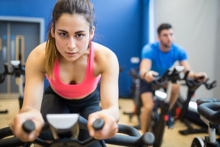 Focused couple using exercise bikes at the gymの写真素材