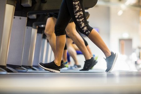 Fit people jogging on treadmills at the gymの写真素材