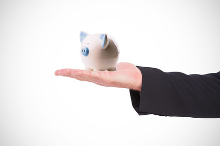 Businessman holding hand out in presentation against piggy bankの写真素材