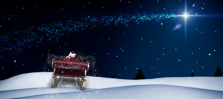 Santa flying his sleigh against shooting star over forest at nightの写真素材