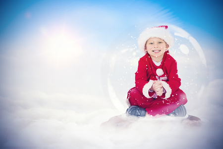 Festive child in snow globe against blue sky with white cloudsの写真素材
