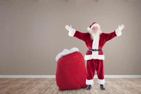Happy santa with sack of gifts against room with wooden floorの写真素材