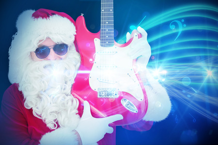 Cool santa showing electric guitar against curved laser light design in blueの写真素材