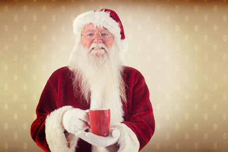 Santa holds a red cup against room with wooden floorの写真素材