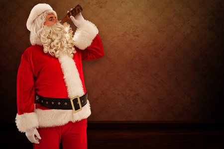 Father christmas drinking a beer against room with wallpaperの写真素材